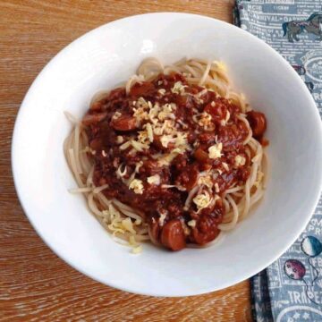 Filipino style spaghetti with red sauce and topping of grated cheese
