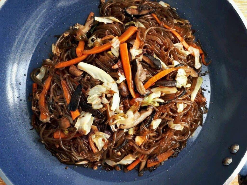 Vegan Japchae Korean Glass Noodles with cabbage, carrots and mushroom in a pan