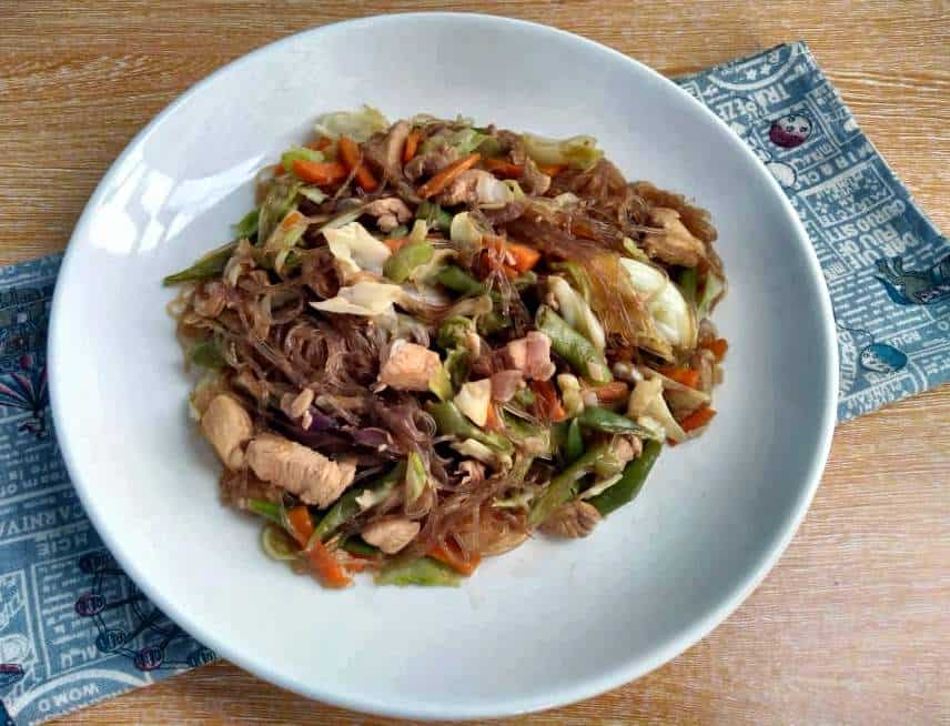 Pancit Sotanghon Guisado with vermicelli noodle, chicken breast, julienne carrots, string beans and cabbage in a plate