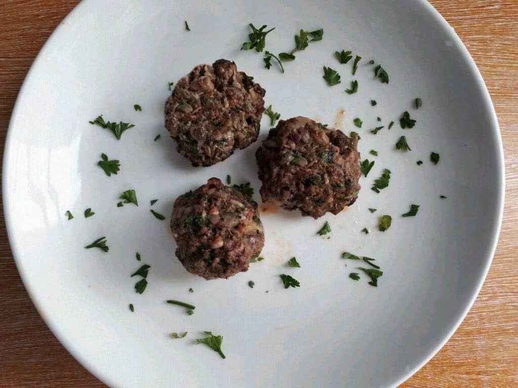 Beef Kofta kebab shaped in a meatball garnished with chopped parsley in a plate.