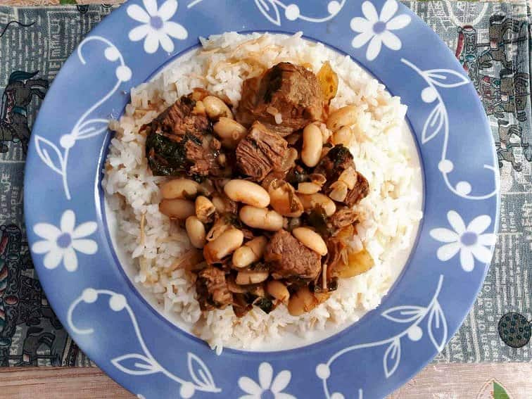 Fasolia Recipe mixed with White beans and boneless beef cubes served on a rice in a plate