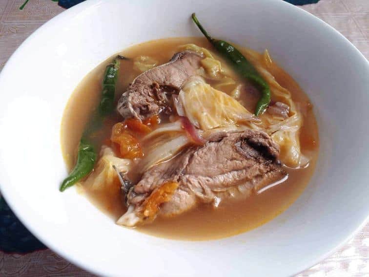 Fish Sinigang Soup Recipe mixed with boneless fish, green chilies, cabbage and tomatoes in a bowl.