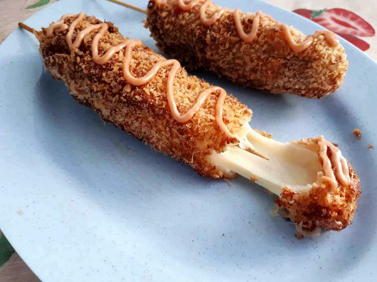 Korean Mozzarella Corn Dog with cheese that is coated in batter & breadcrumb and drizzle with mayo ketchup sauce