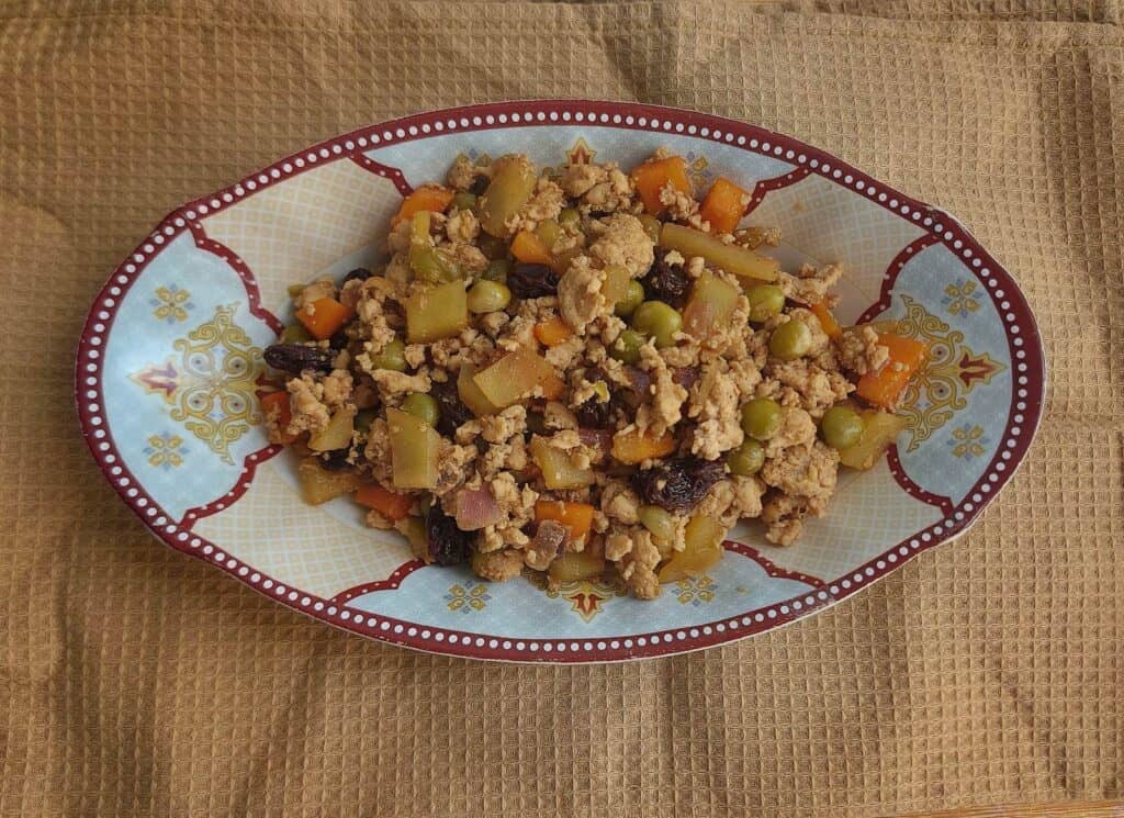 A filipino ground meat dish Chicken giniling mixed with raisins, chickpeas, potatoes and carrots serve in a plate