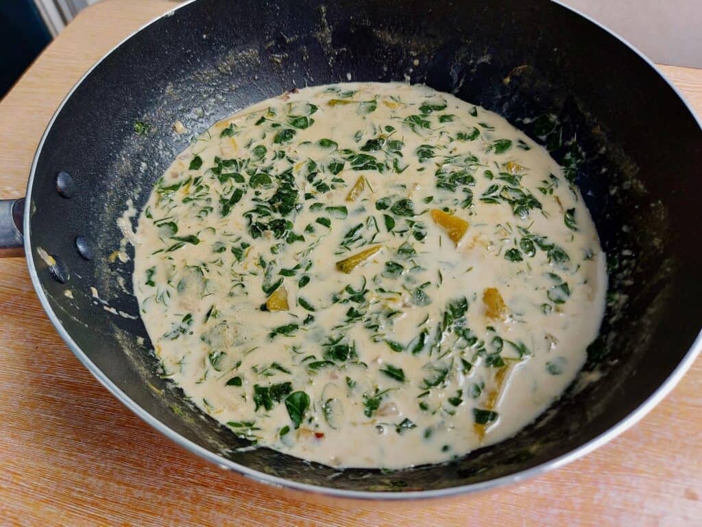 A Filipino vegetarian stew recipe Ginataang Kalabasa mixed with coconut milk, squash, and malunggay (moringa) leaves served on a plate bowl.