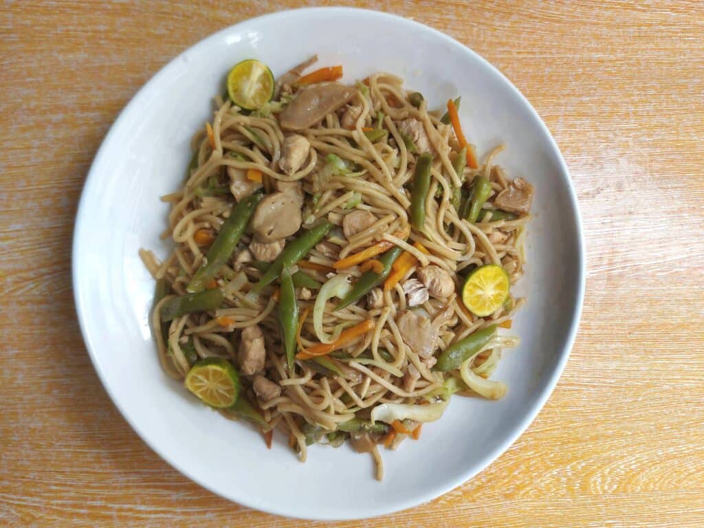 Chicken Pancit Canton noodle recipe mixed with green beans, julienned carrot, and chopped chicken breast served with calamansi.