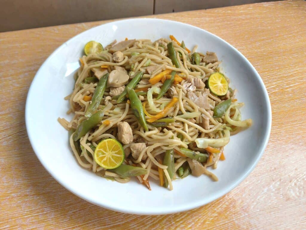 Chicken Pancit Canton noodle recipe mixed with green beans, julienned carrot, and chopped chicken breast served with calamansi.
