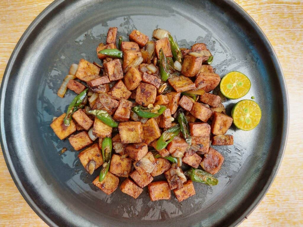 A filipino tofu sisig with green chilies and calamansi served on a plate