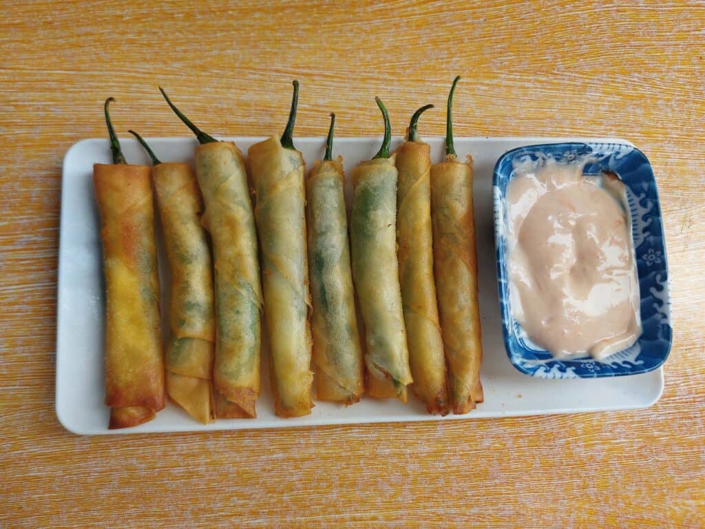 A Filipino Chili Cheese Stick Dynamite lumpia served with mayo-ketchup sauce on a plate