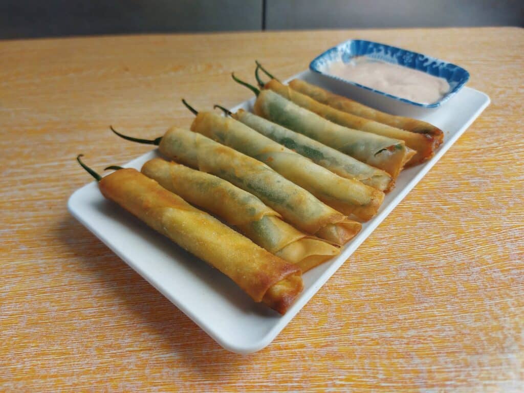 A Filipino Chili Cheese Stick Dynamite lumpia served with mayo-ketchup sauce on a plate