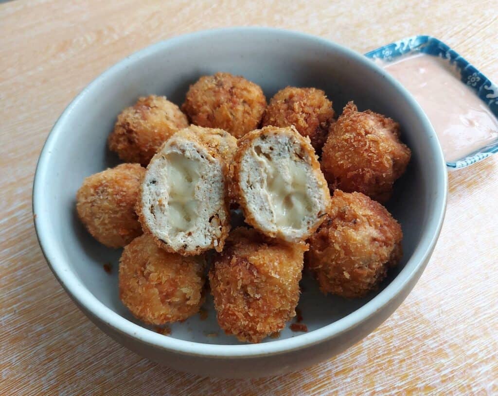 Chicken nugget with cheese with one slices open served on a plate