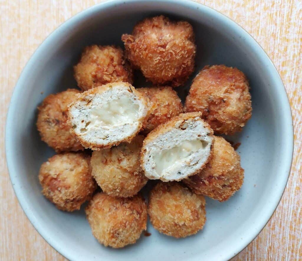 Chicken nugget with cheese with one slices open served on a plate