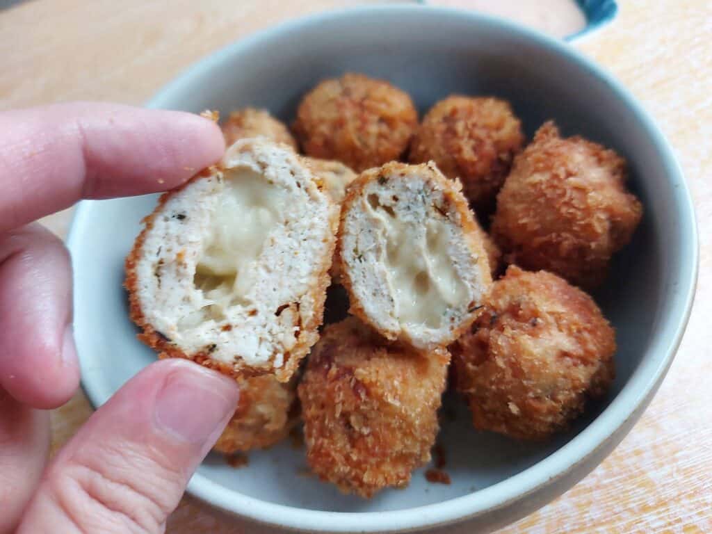 Chicken nugget with cheese with one slices open served on a plate