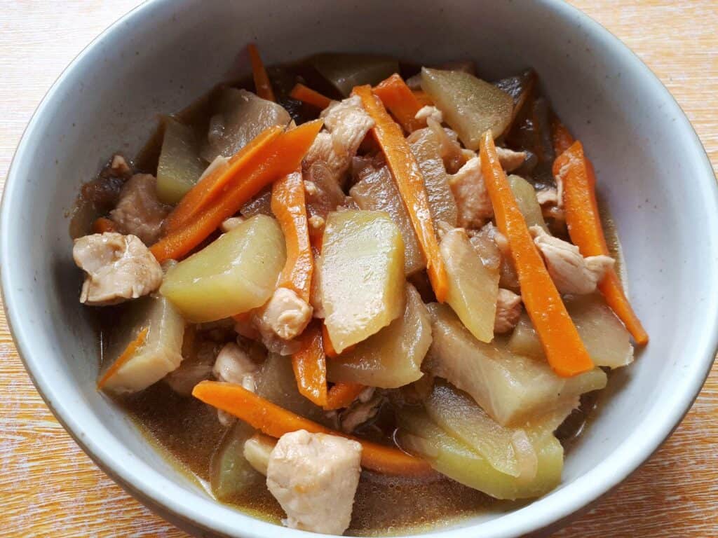 Filipino Chayote recipe Ginisang Sayote with julienned carrot and chopped chicken breast served on a plate bowl