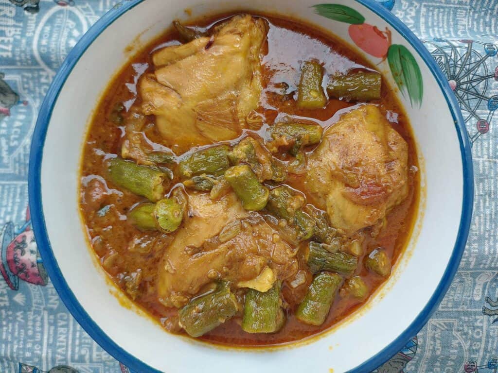 Chicken Bhindi with okra, chicken thigh, tomato gravy sauce serve on a plate bowl.