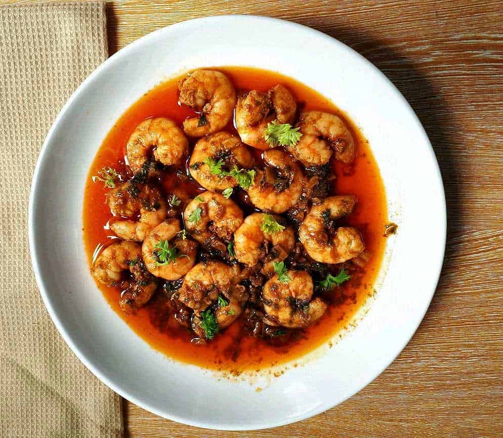 Spanish Garlic Prawns, also known as Gambas Al Ajillo, consist of garlics, prawns, garnished with parsley sauteed in olive oil with paprika served on a plate.
