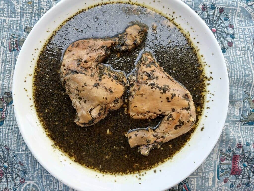 Chicken Molokhia: Middle Eastern green stew with chicken, molokhia leaves, garlic, herbs, and spices served on a plate.