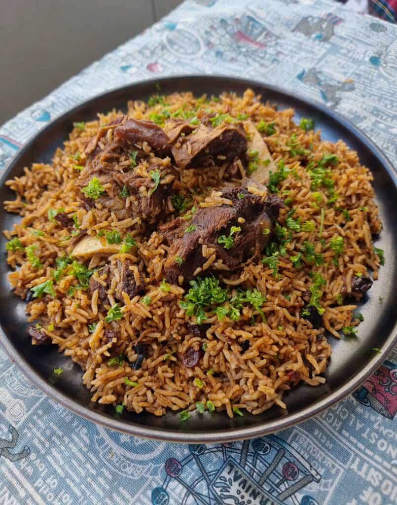 Beef Kabsa with aromatic long-grain rice with different spices garnished with chopped parlsey served in a plate.