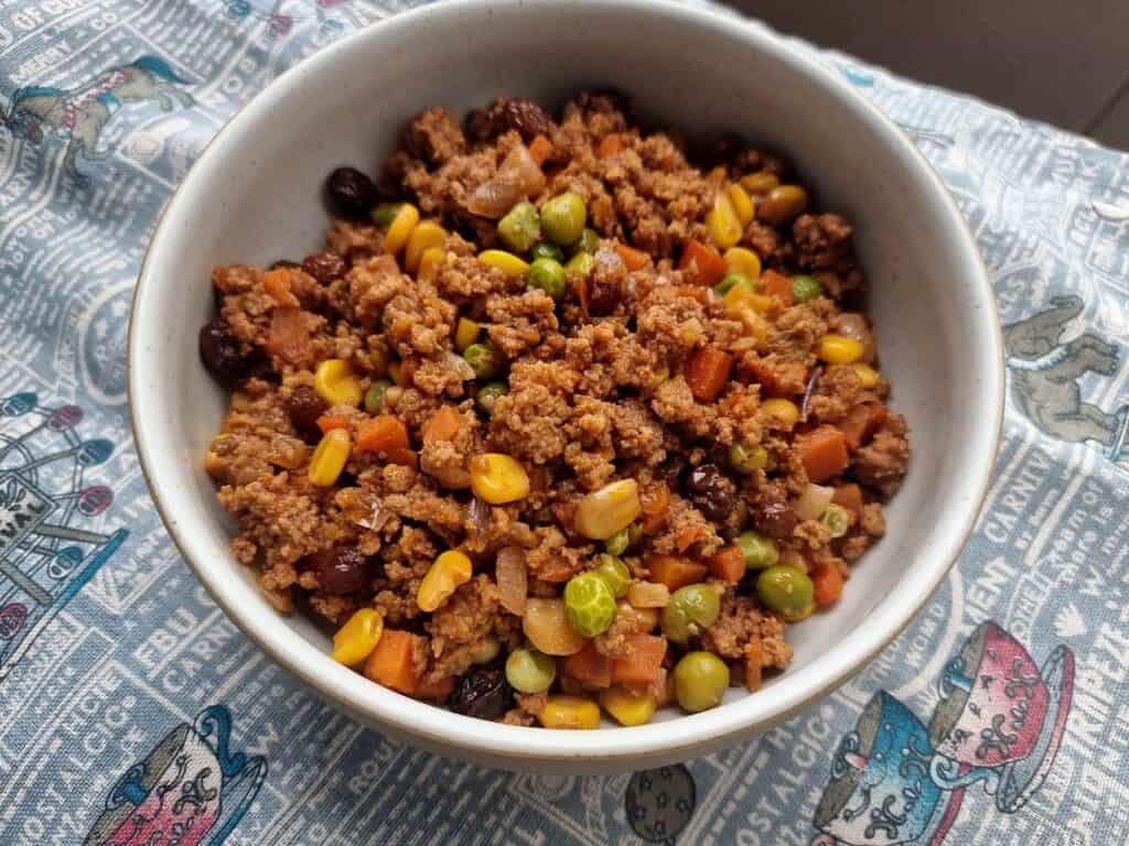 Filipino Beef Giniling mixed with ground beef, corn, carrots, green peas, raisins, and sauces served on a plate.