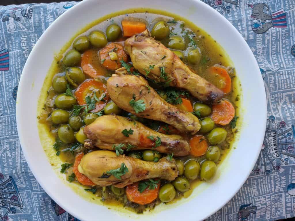 Tajine Zitoune: Algerian chicken stew with carrots, olives, and North African spices served on a plate.