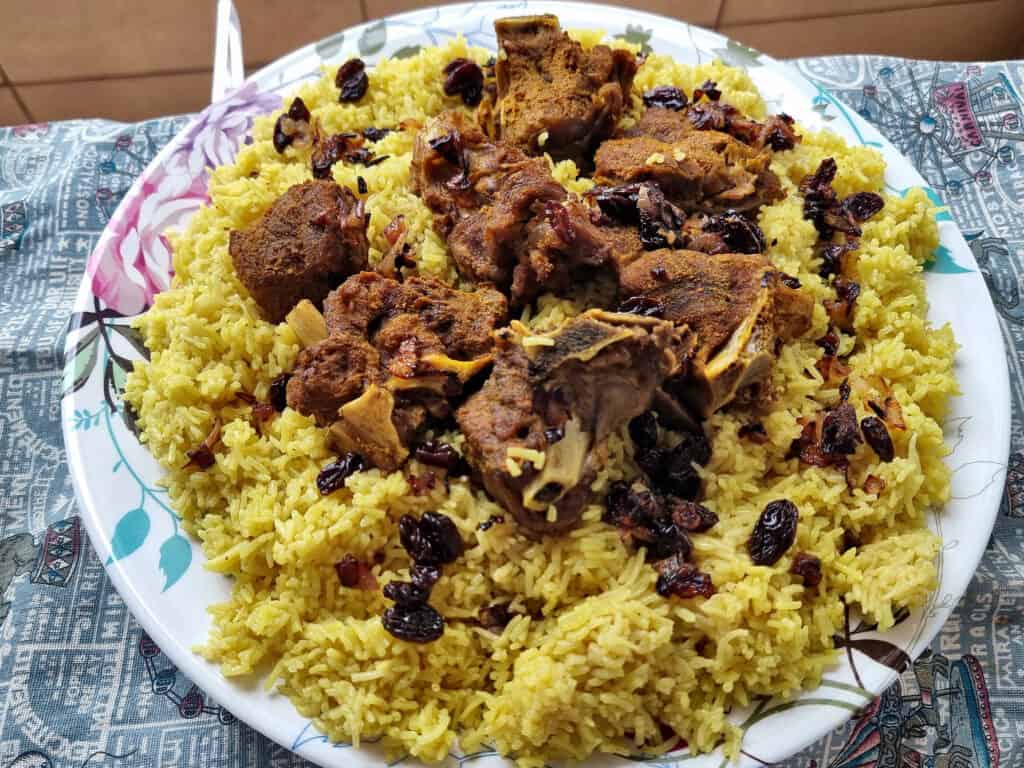 Beef Mandi recipe consists of beef, raisins, fried onion and basmati yellow rice served on a plate