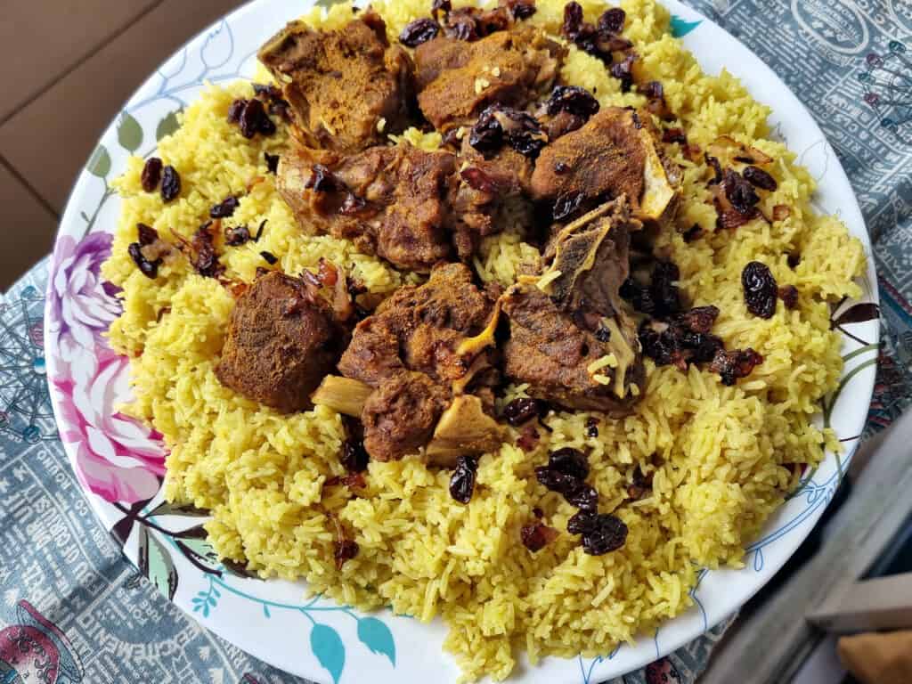 Beef Mandi recipe consists of beef, raisins, fried onion and basmati yellow rice served on a plate