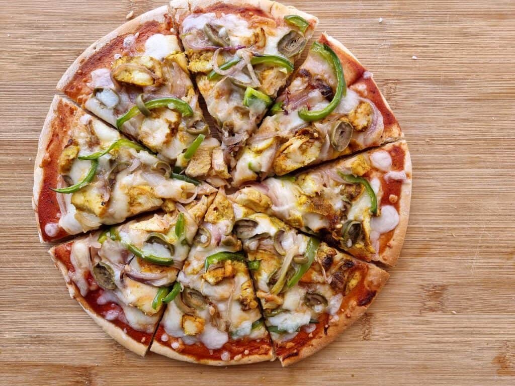 Chicken Shawarma Pizza spread with tomato sauce with chopped chicken, sliced bell pepper & onions and topped with mozzarella cheese.