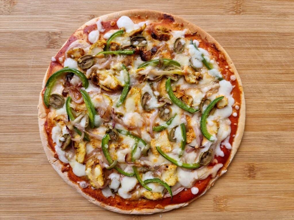 Chicken Shawarma Pizza spread with tomato sauce with chopped chicken, sliced bell pepper & onions and topped with mozzarella cheese.