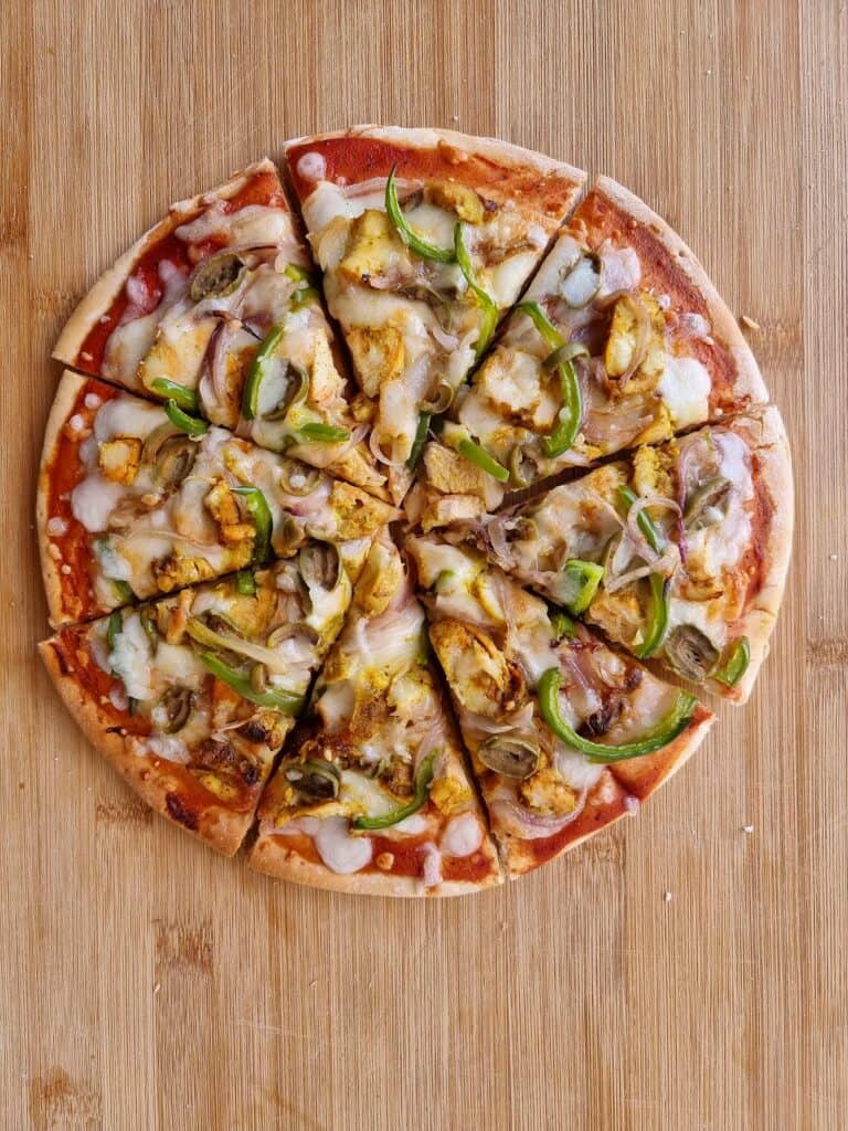 Chicken Shawarma Pizza spread with tomato sauce with chopped chicken, sliced bell pepper & onions and topped with mozzarella cheese.