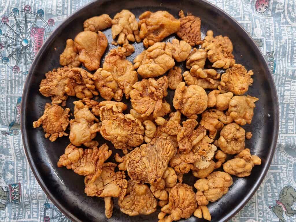 A Filipino vegetarian snack Mushroom chicharon made by thinly slicing, seasoning, and deep-frying mushrooms to achieve a crispy texture