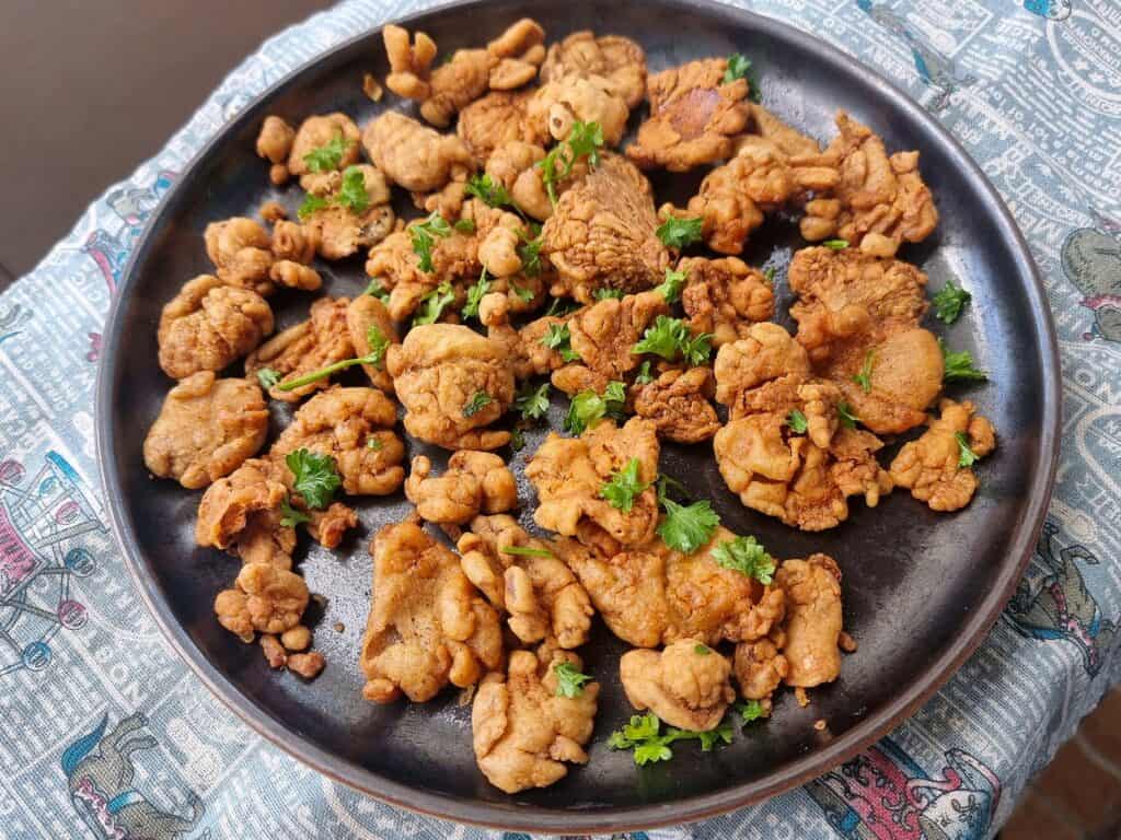 A Filipino vegetarian snack Mushroom chicharon made by thinly slicing, seasoning, and deep-frying mushrooms to achieve a crispy texture