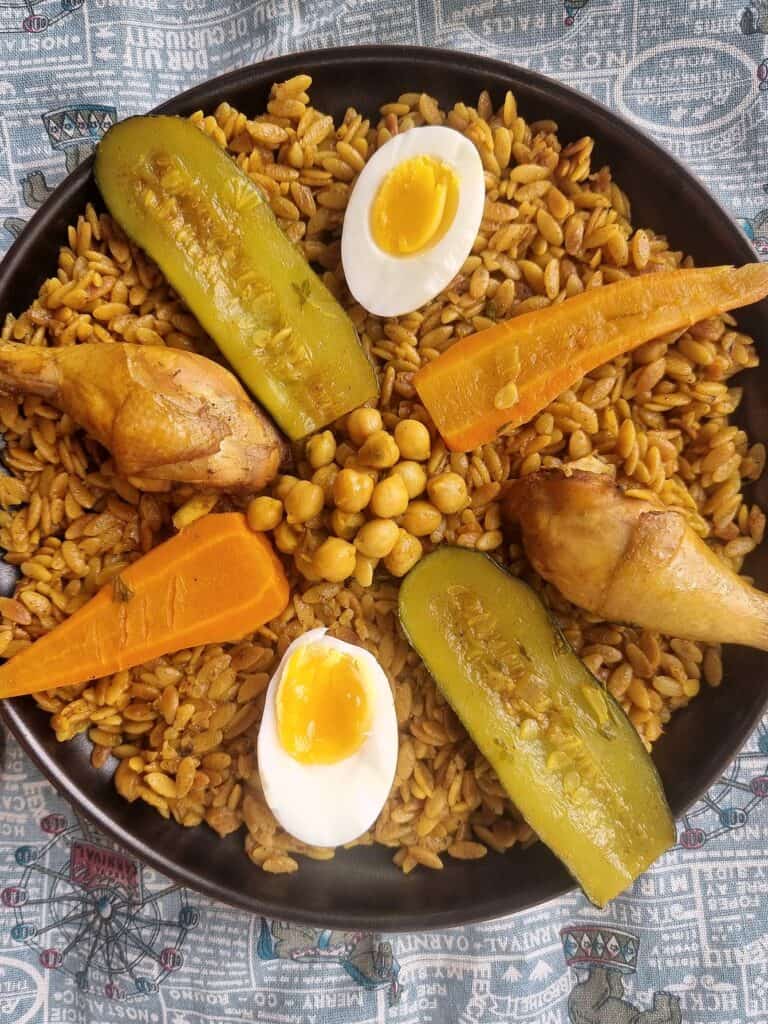 An Algerian Tlitli served with chicken drumstick, baton-cut zucchini, carrots, chickpeas in broth, served with layered boiled egg over orzo pasta.