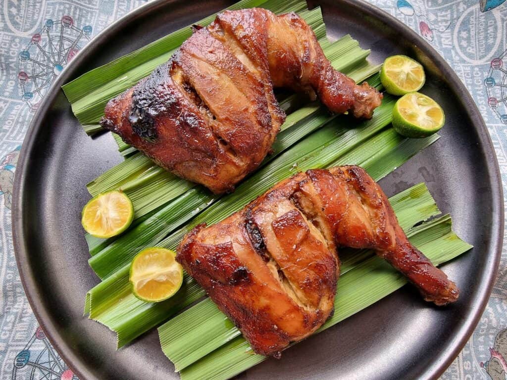 A Filipino bacolod chicken inasal recipe with banana leave below and pieces of calamansi served in a plate.