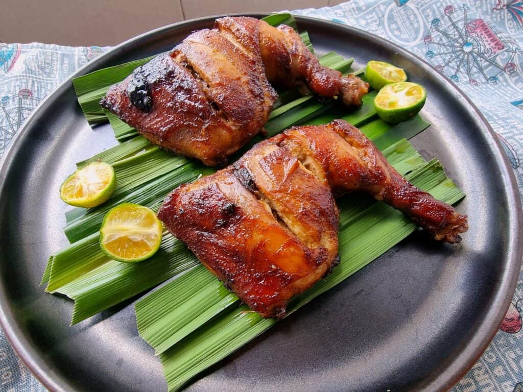 A Filipino bacolod chicken inasal recipe with banana leave below and pieces of calamansi served in a plate.