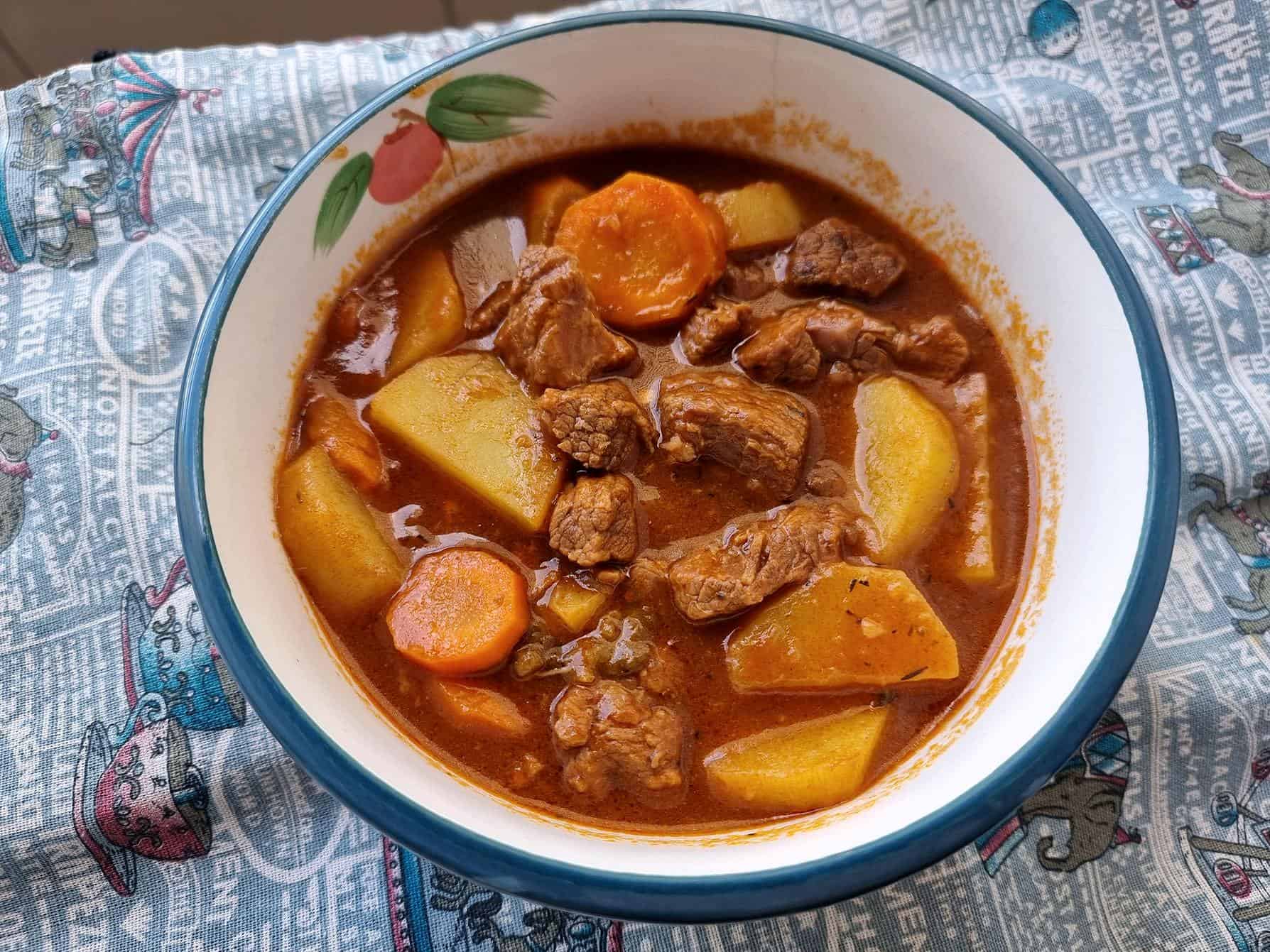 Turkish beef stew tas kebab recipe containing beef fillet, potatoes, carrots in a tomato broth stew served in a plate bowl.
