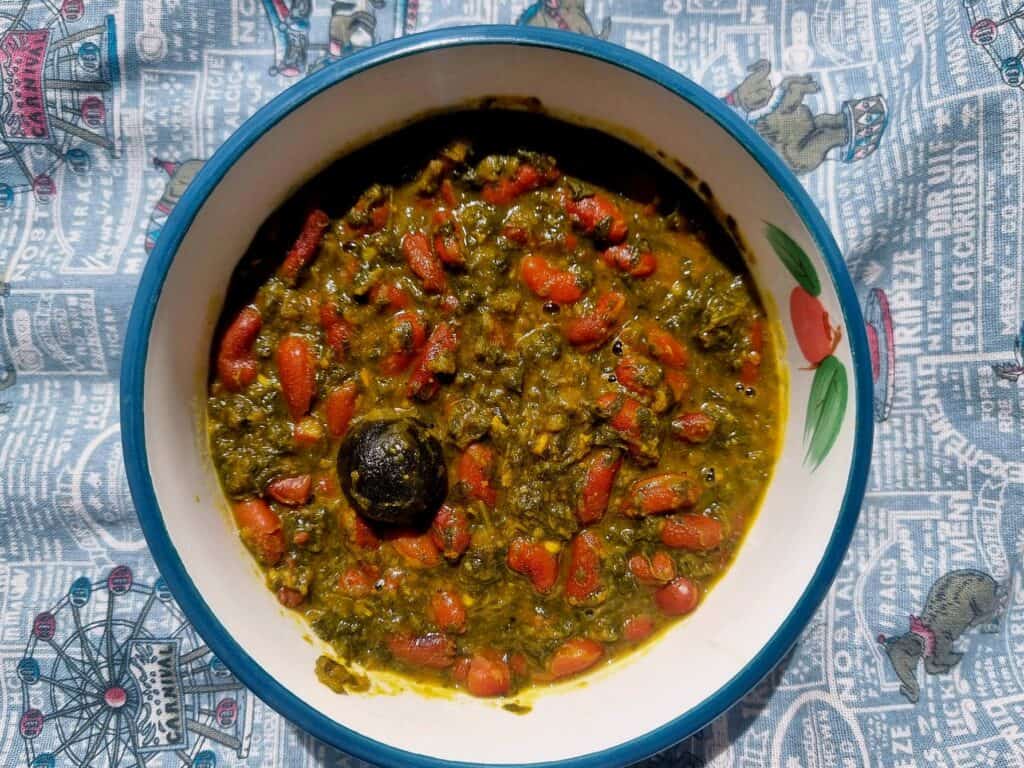 Iranian stew Ghormeh Sabzi recipe mixed with different herbs, kidney beams, dried lime and other spices served in a plate bowl