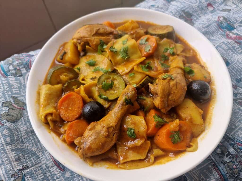 Margoog recipe with chicken, different spices, carrots, potatoes and zucchini, and raw dough that is added to the stew.