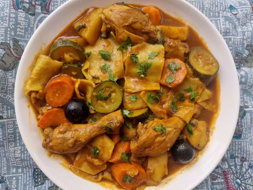 Margoog recipe with chicken, different spices, carrots, potatoes and zucchini, and raw dough that is added to the stew.
