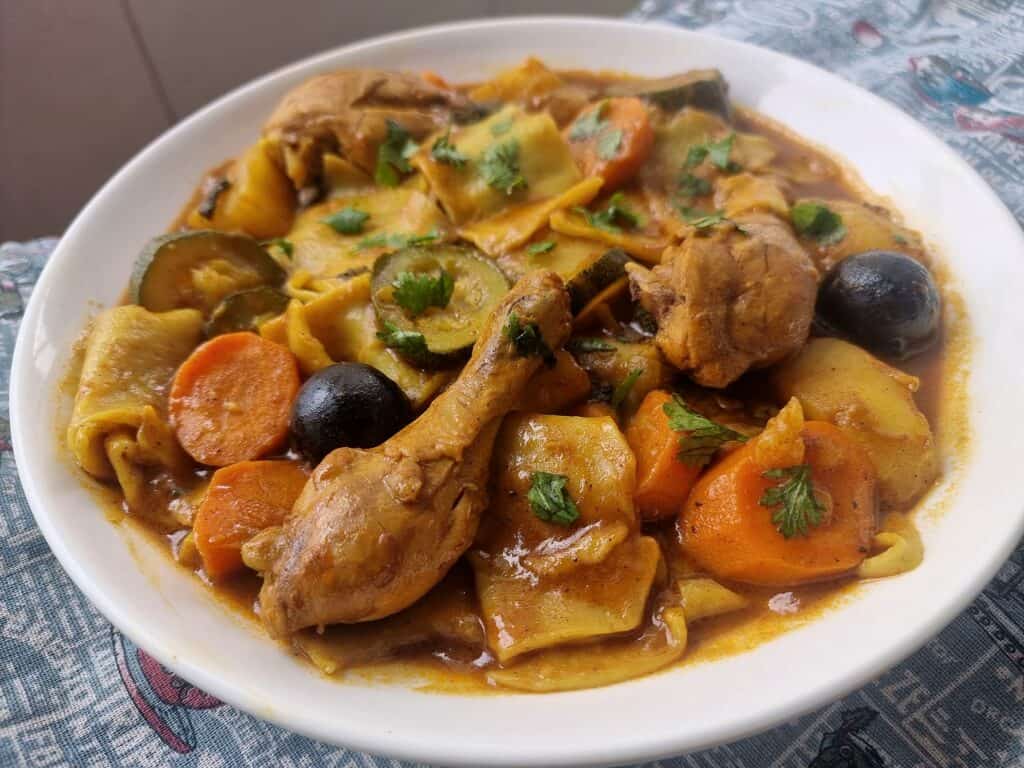 Margoog recipe with chicken, different spices, carrots, potatoes and zucchini, and raw dough that is added to the stew.