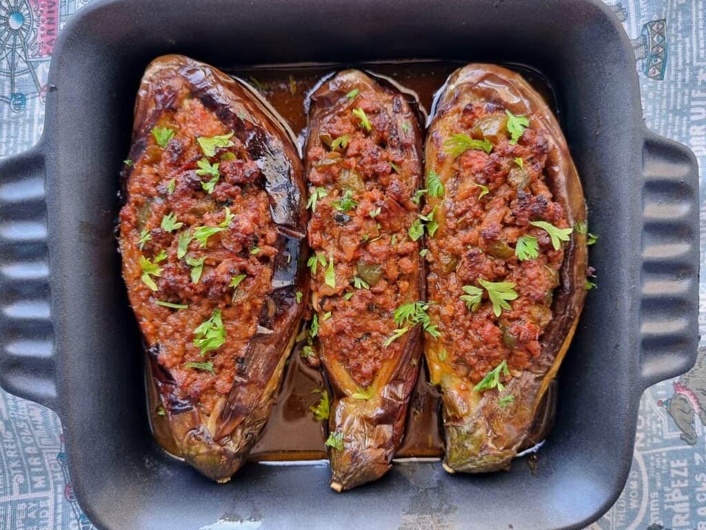 Turkish Stuffed Eggplants called Karniyarik which is stuffed with seasoned ground beef, onions, tomatoes, and green peppers garnished with chopped parsley leaves.