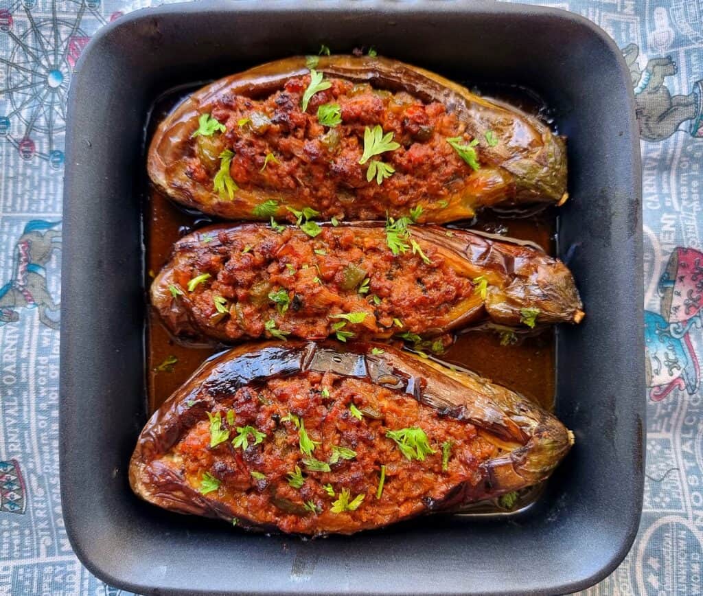 Turkish Stuffed Eggplants called Karniyarik which is stuffed with seasoned ground beef, onions, tomatoes, and green peppers garnished with chopped parsley leaves.