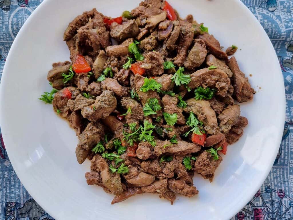 Egyptian Liver Kebda Eskandarani with chopped bell pepper and sprinkled with chopped parsley served on a plate