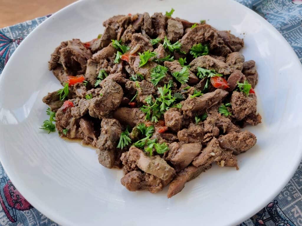 Egyptian Liver Kebda Eskandarani with chopped bell pepper and sprinkled with chopped parsley served on a plate