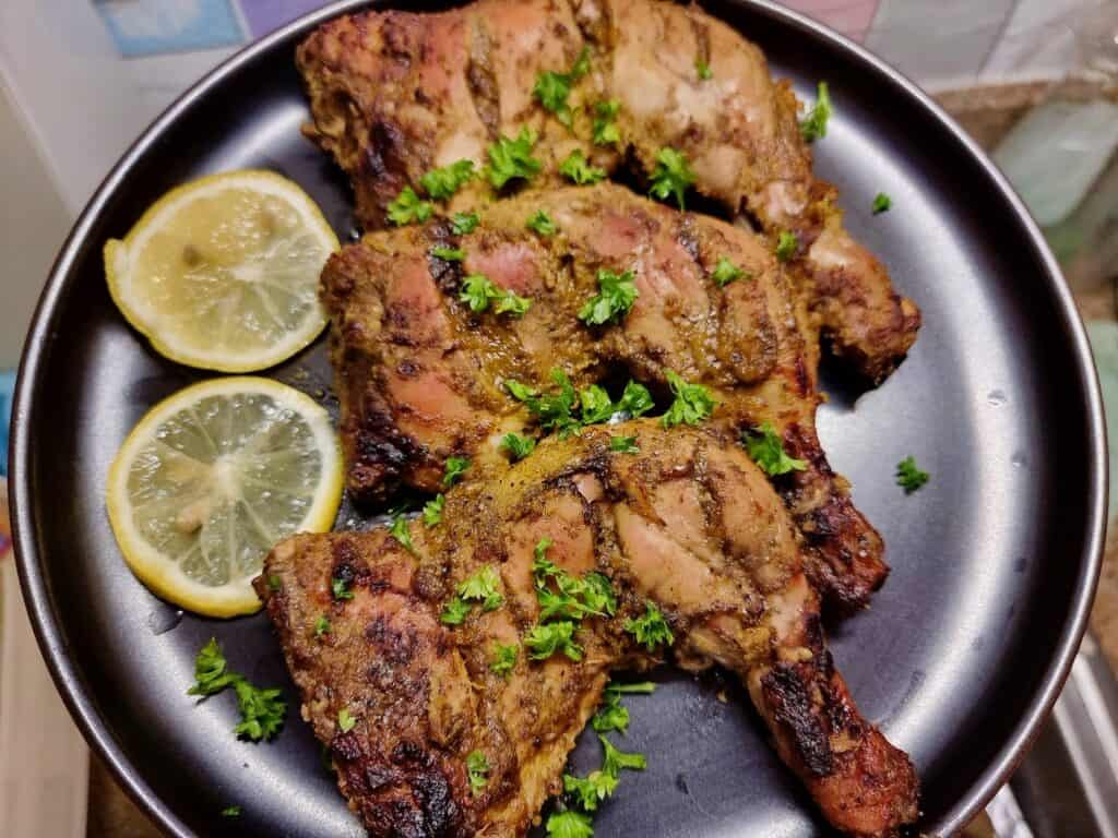 Arabic grilled chicken Al faham chicken that is garnished with parsley and serve with slices of lemon on a plate