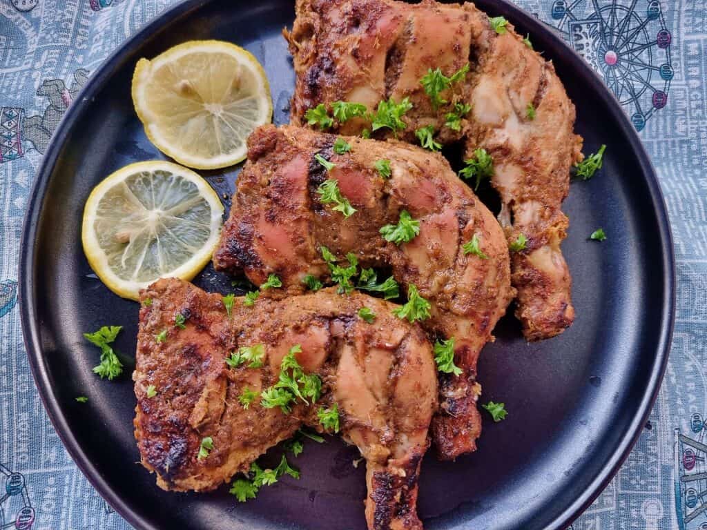 Arabic grilled chicken Al faham chicken that is garnished with parsley and serve with slices of lemon on a plate